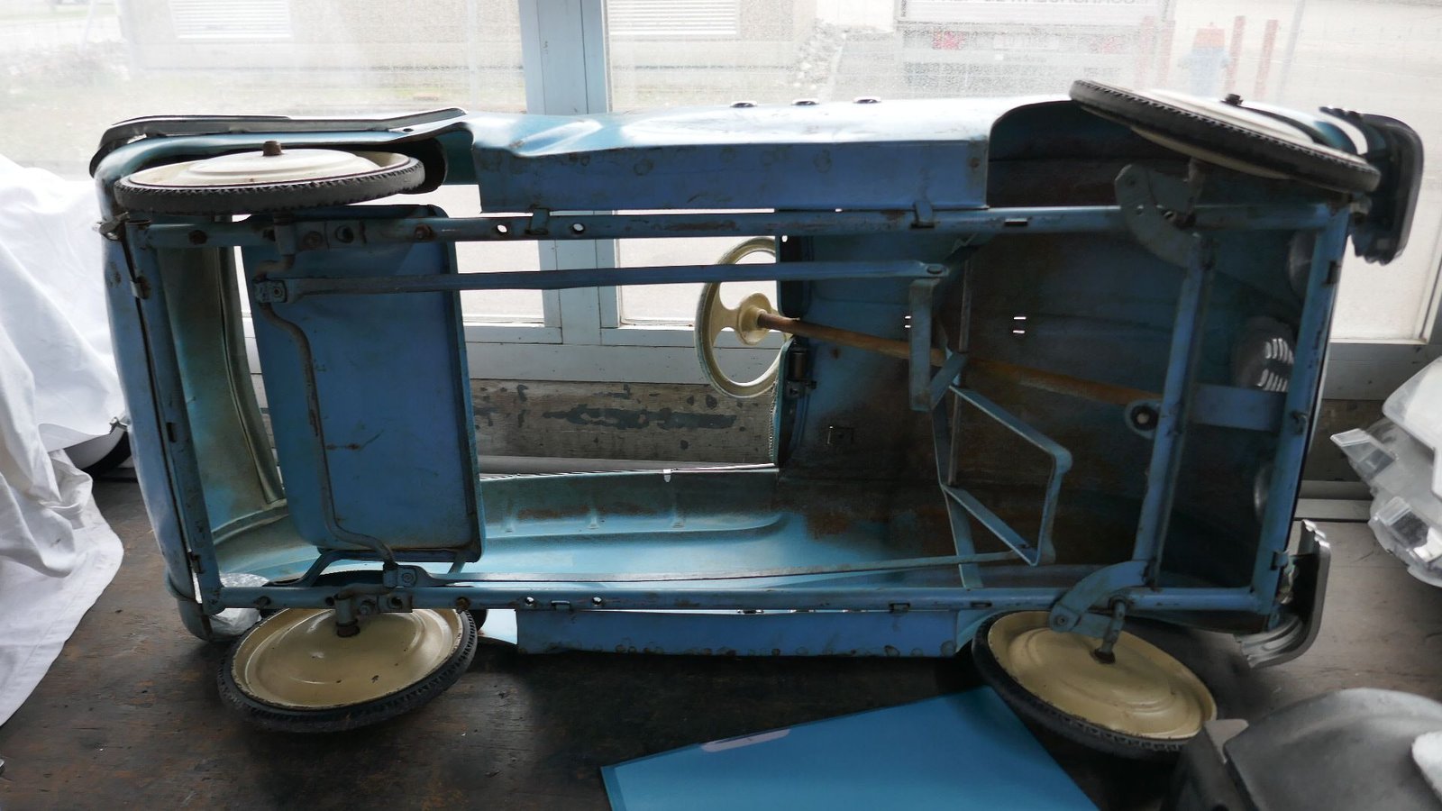 Ein blaues Tretauto steht auf einem Tisch vor einem Fenster.